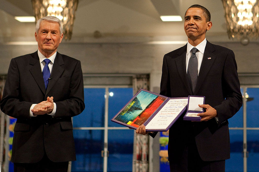 Obama segurando o prêmio Nobel ao lado de Thorbjørn Jagland